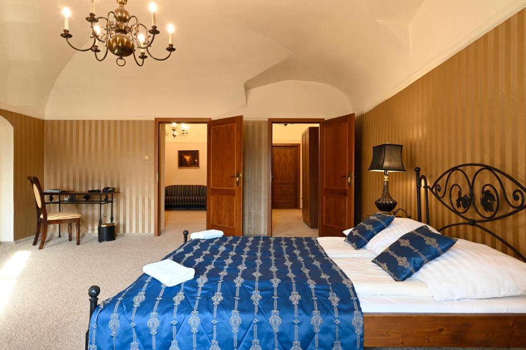 a bedroom with a large bed with a blue blanket at Hotel Bouček in Kroměříž