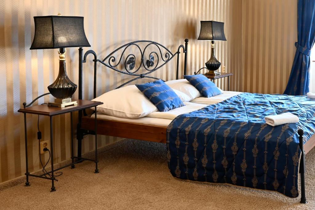 a bedroom with a bed with two lamps on tables at Hotel Bouček in Kroměříž