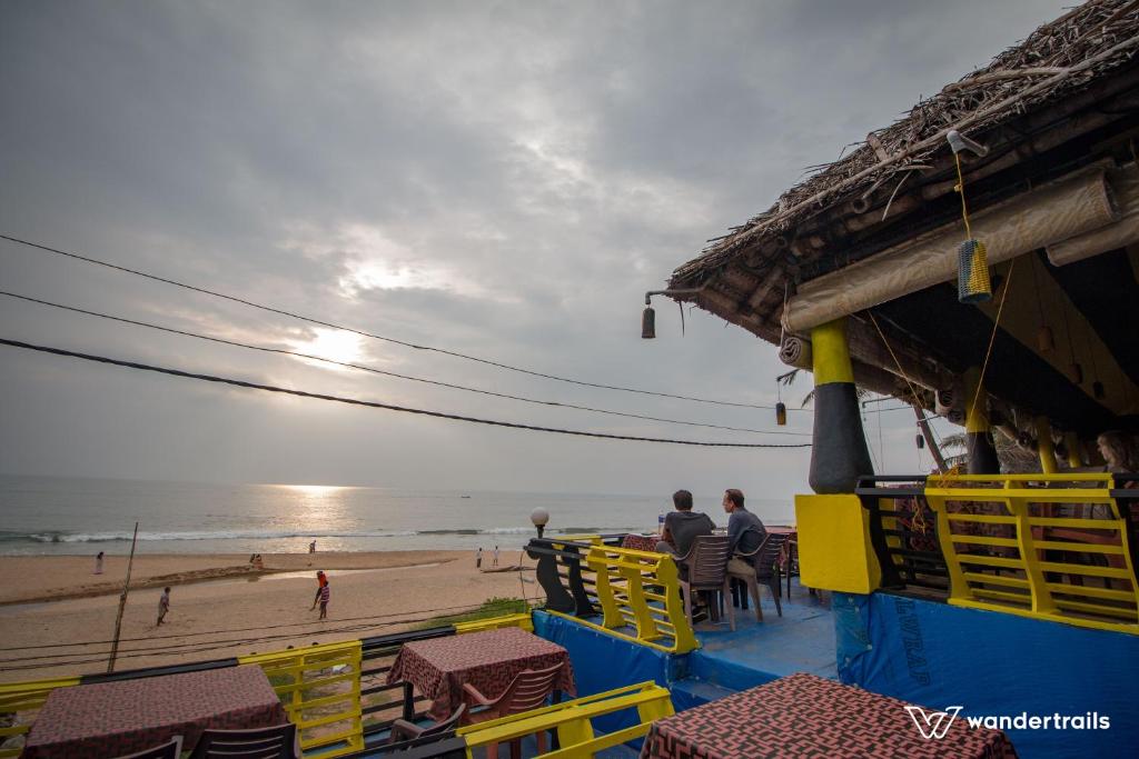 a beach bar with yellow chairs and a view of the ocean at Varkala Marine Palace in Varkala