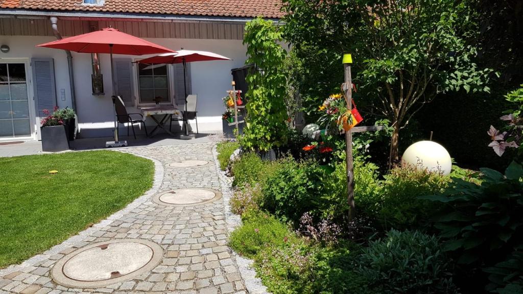 einen Garten mit einer Terrasse mit einem Tisch und einem Sonnenschirm in der Unterkunft Ferienhaus Schönebühl in Oberreute