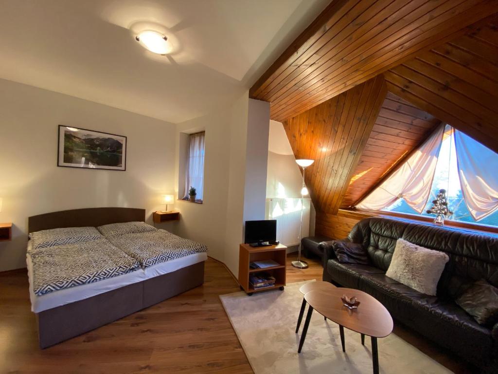 a bedroom with a bed and a couch at Penzion Gabriel in Nový Smokovec