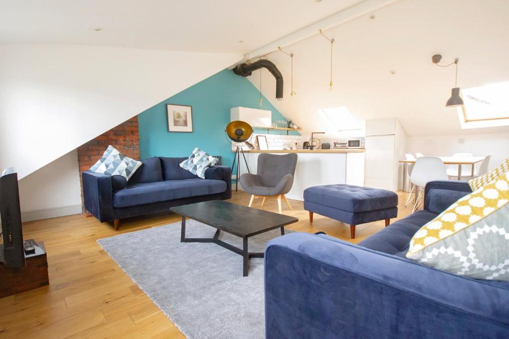 ein Wohnzimmer mit 2 blauen Sofas und einem Tisch in der Unterkunft The Loft Winchester in Winchester