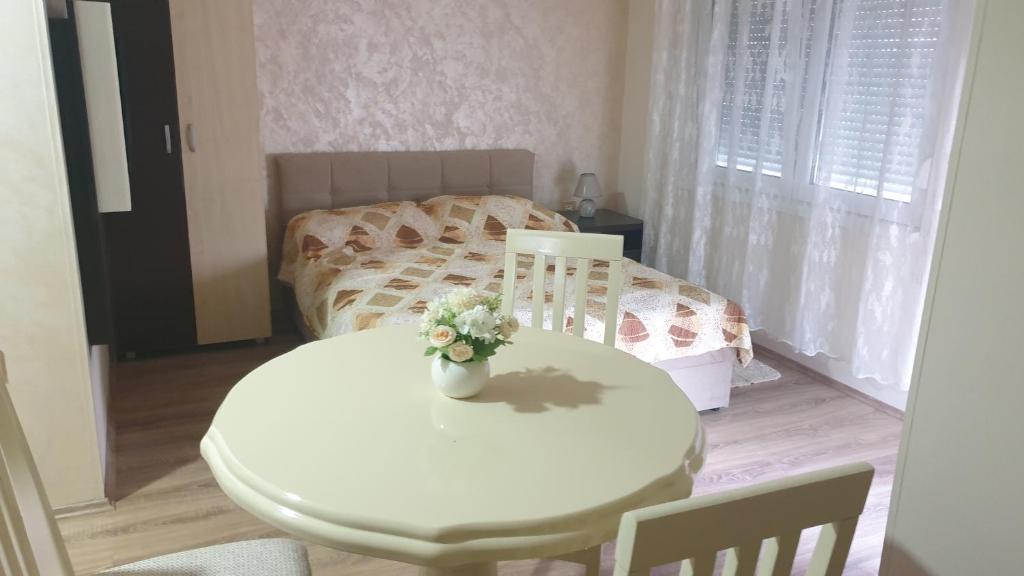 Una mesa blanca con un jarrón de flores. en Apartments Kamenjar en Novi Sad