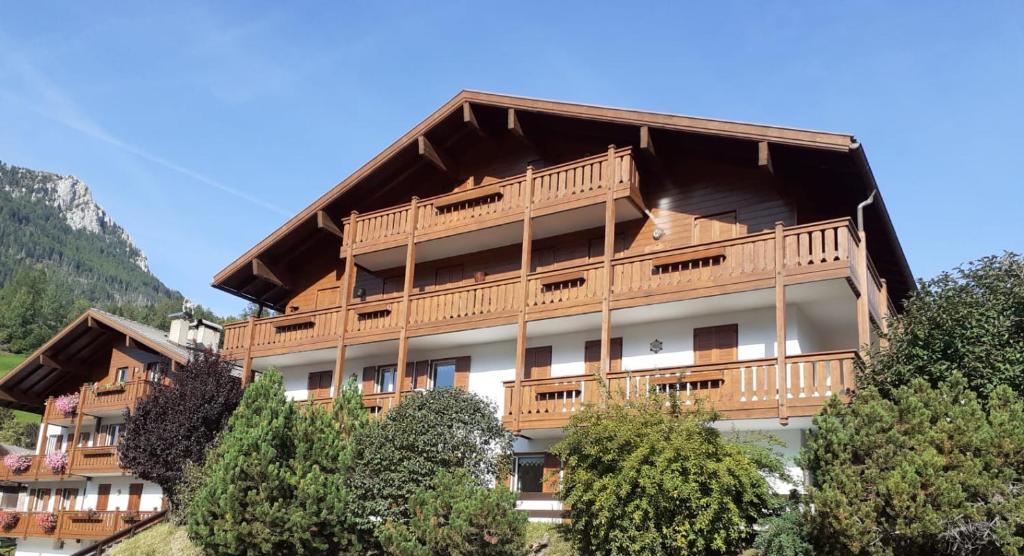 un gran edificio con balcones de madera y árboles en Vacanzemoena - Cielo Azzurro, tipologia 1, en Moena
