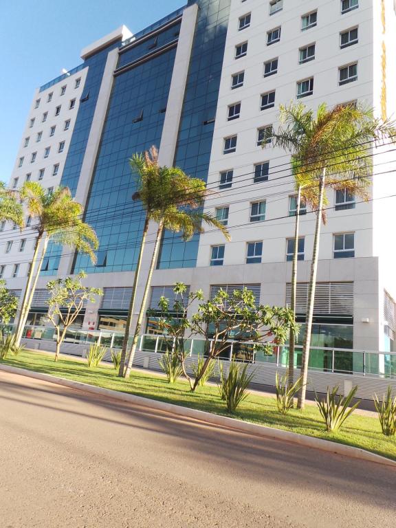 a building with palm trees in front of a road at Flat Particular Jade Brasilia 1004 e 1006 Com Garagem in Brasilia