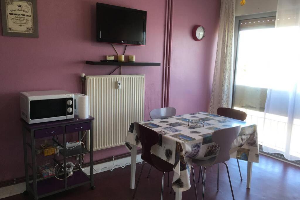 ein Esszimmer mit einem Tisch und einem TV in der Unterkunft Studio meublé 28m2 vue côté Balaruc centre et massif de la Gardiole in Balaruc-les-Bains