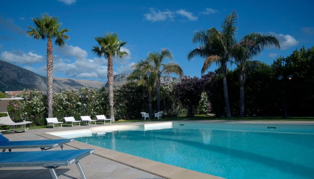 una piscina con sedie e palme di Panoramica Villa con Piscina sul Mare (Sanificata) a Cinisi