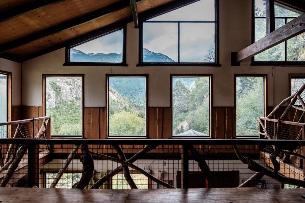 a room with windows with mountains in the background at Hostal Las Natalias in Futaleufú
