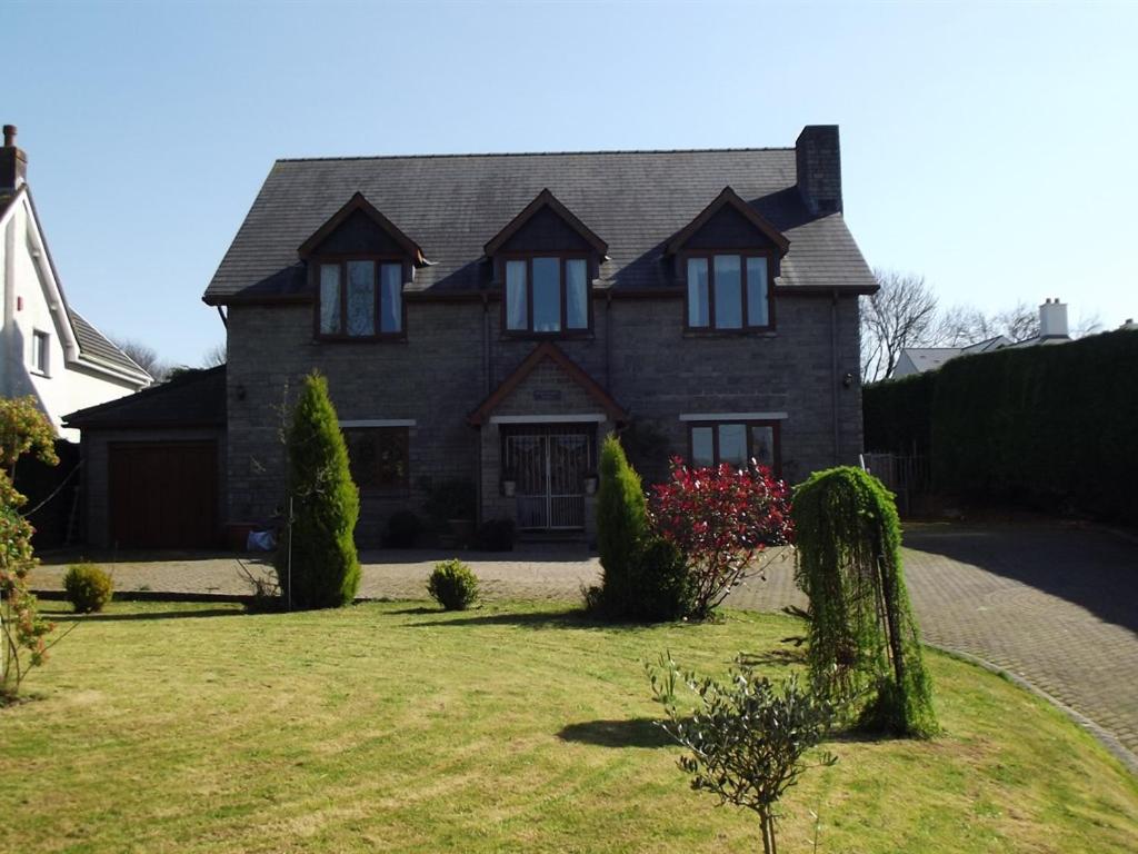 a large brick house with a grass yard at Bryngower House in Llanrhidian