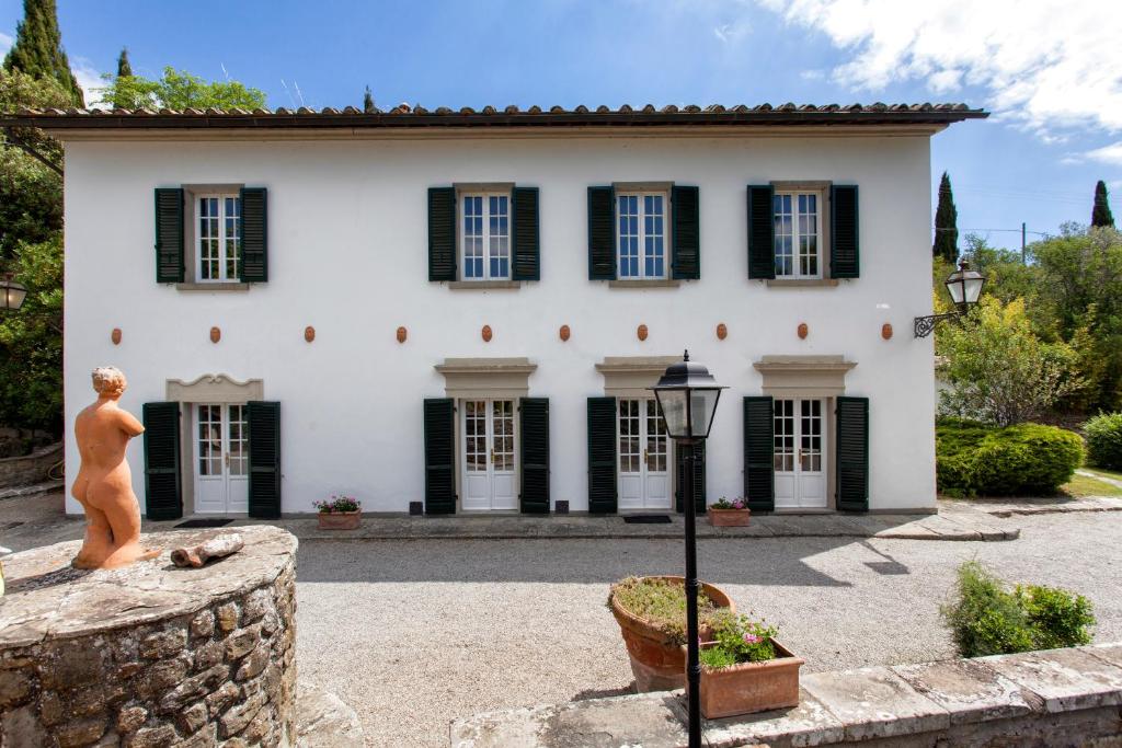 una gran casa blanca con persianas negras en Villa Serena & Dépendances, en Cortona