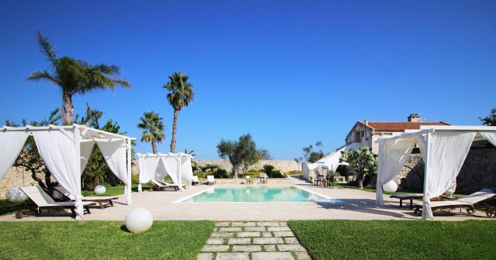 una piscina con gazebo bianchi e sedie intorno ad essa di Don Agostino Relais Masseria a Martano