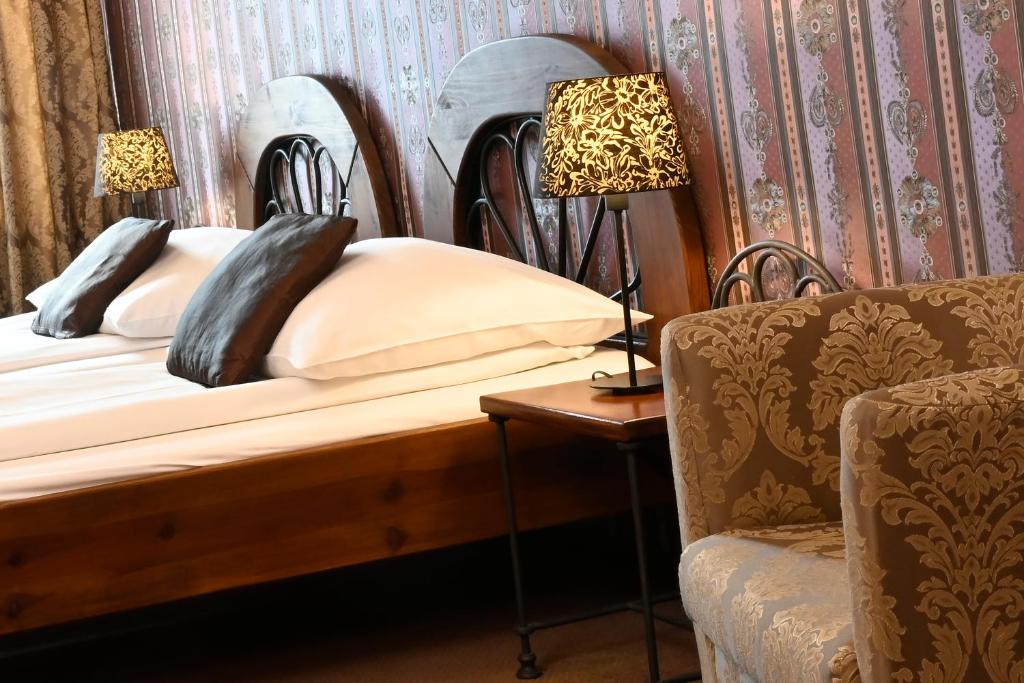 a bedroom with a bed and a chair and lamps at Hotel Bouček in Kroměříž