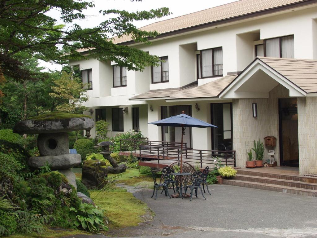 a house with a table and chairs and an umbrella at Teiensaryo Yamanakako in Yamanakako