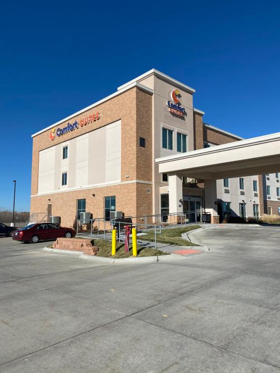 a building with a car parked in a parking lot at Comfort Suites West Omaha in Omaha