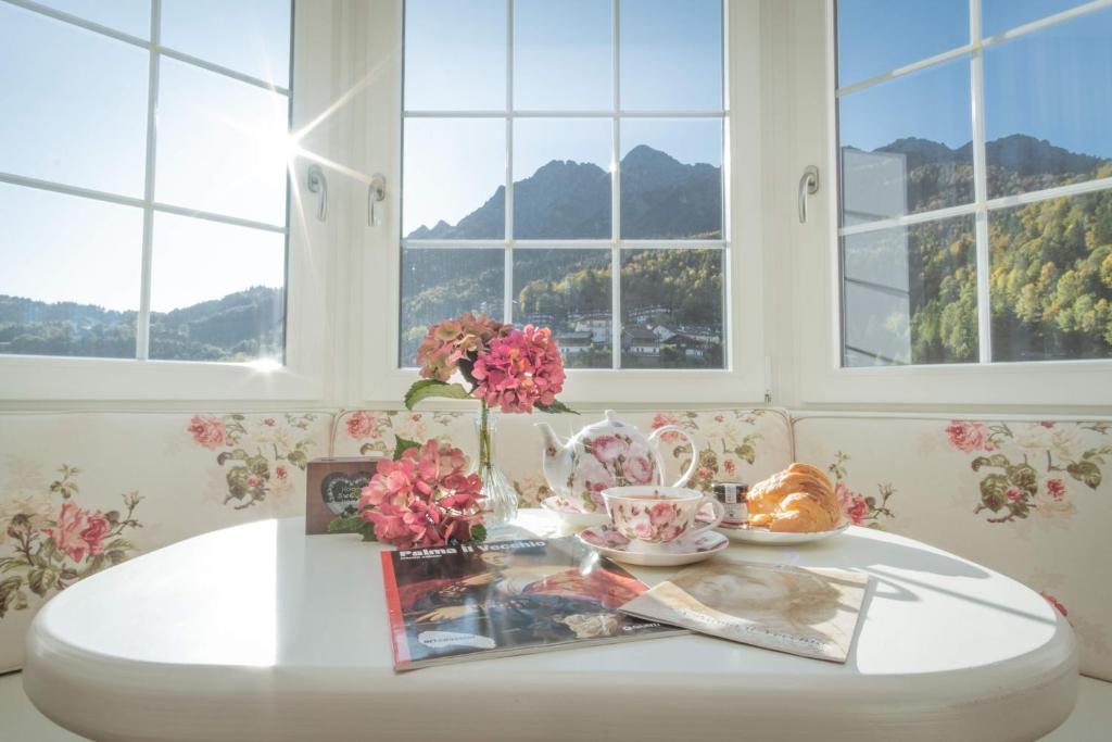 B&B Casa Dolce Casa في Oltre il Colle: طاولة بيضاء عليها زهور في غرفة بها نوافذ