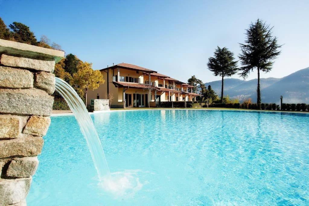 a swimming pool with a water fountain in front of a house at TREMEZZO RESIDENCE 2 in Tremezzo