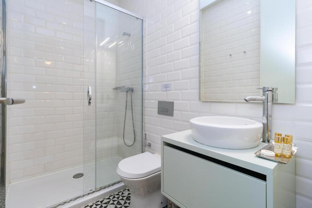 ein weißes Bad mit einem Waschbecken und einer Dusche in der Unterkunft Oporto Cozy & Comfy in Porto