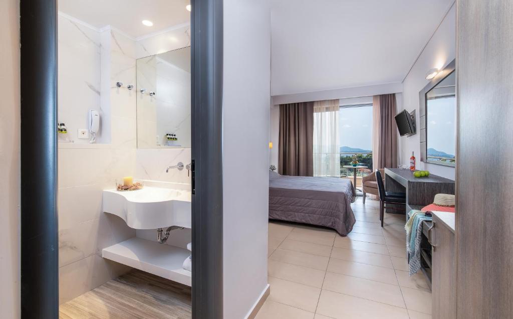 a bathroom with a sink and a bedroom with a bed at Lagomandra Hotel and Spa in Lagomandra