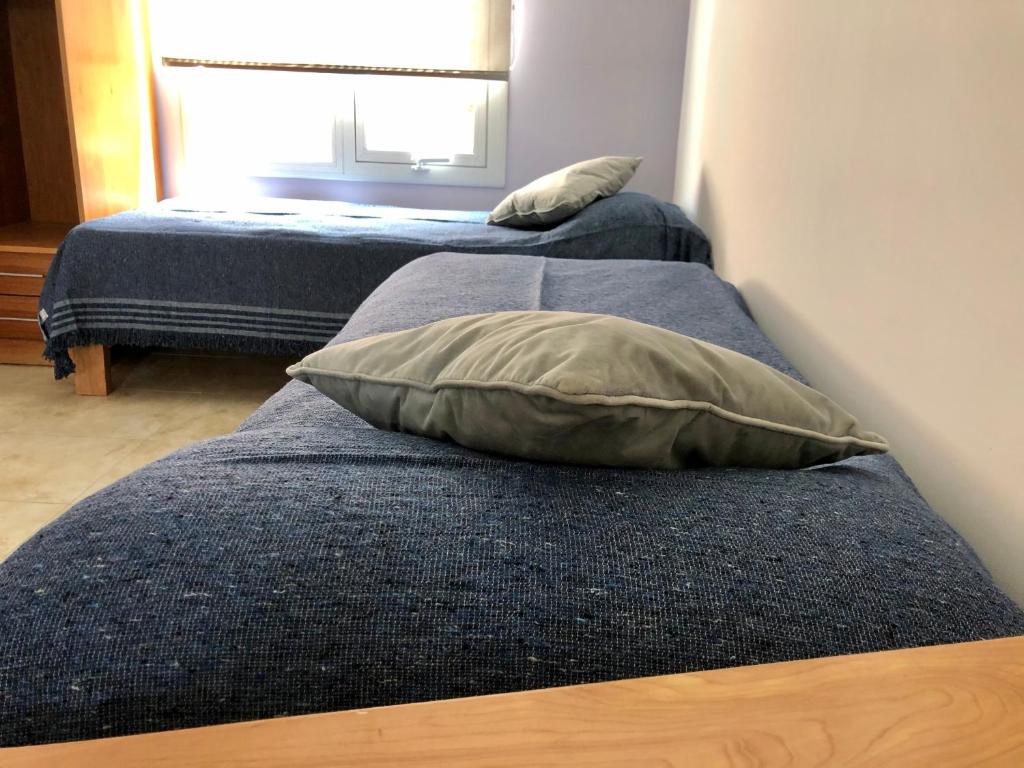 2 camas con almohadas en una habitación con ventana en Polo Aparts en El Chaltén