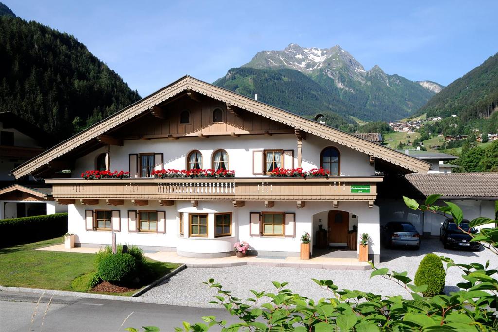 a white house with red flowers on the balcony at Landhaus Michael in Mayrhofen