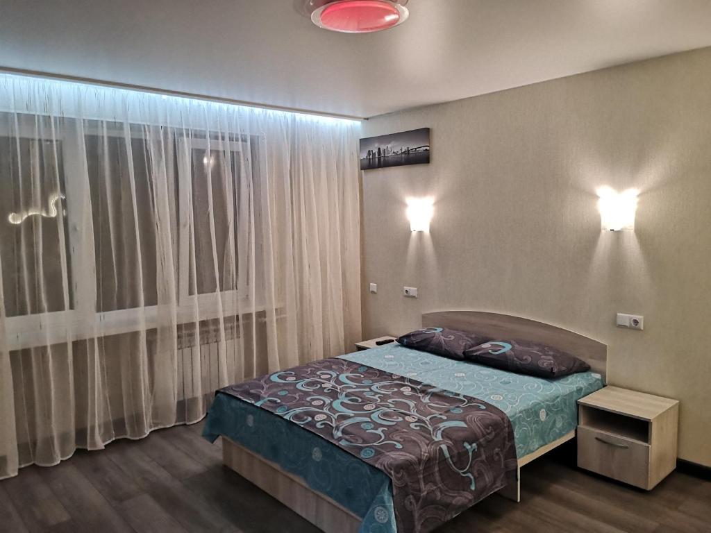 a bedroom with a bed and a large window at НОВАЯ КВАРТИРА на пр. Соборном возле ЗНУ in Zaporozhye