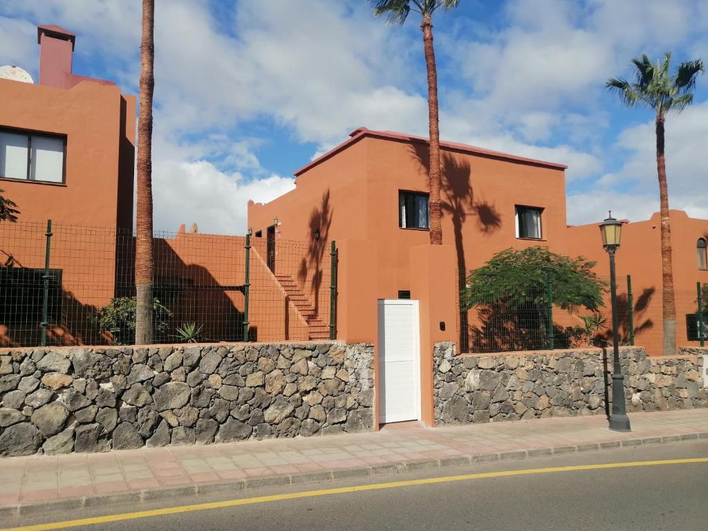 - un bâtiment avec un mur en pierre et une porte blanche dans l'établissement Small&Sunny WiFi Premium vivienda vacacional, à Corralejo
