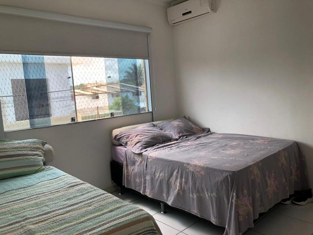 a small bedroom with two beds and a window at Casa de Fábio in Porto Seguro