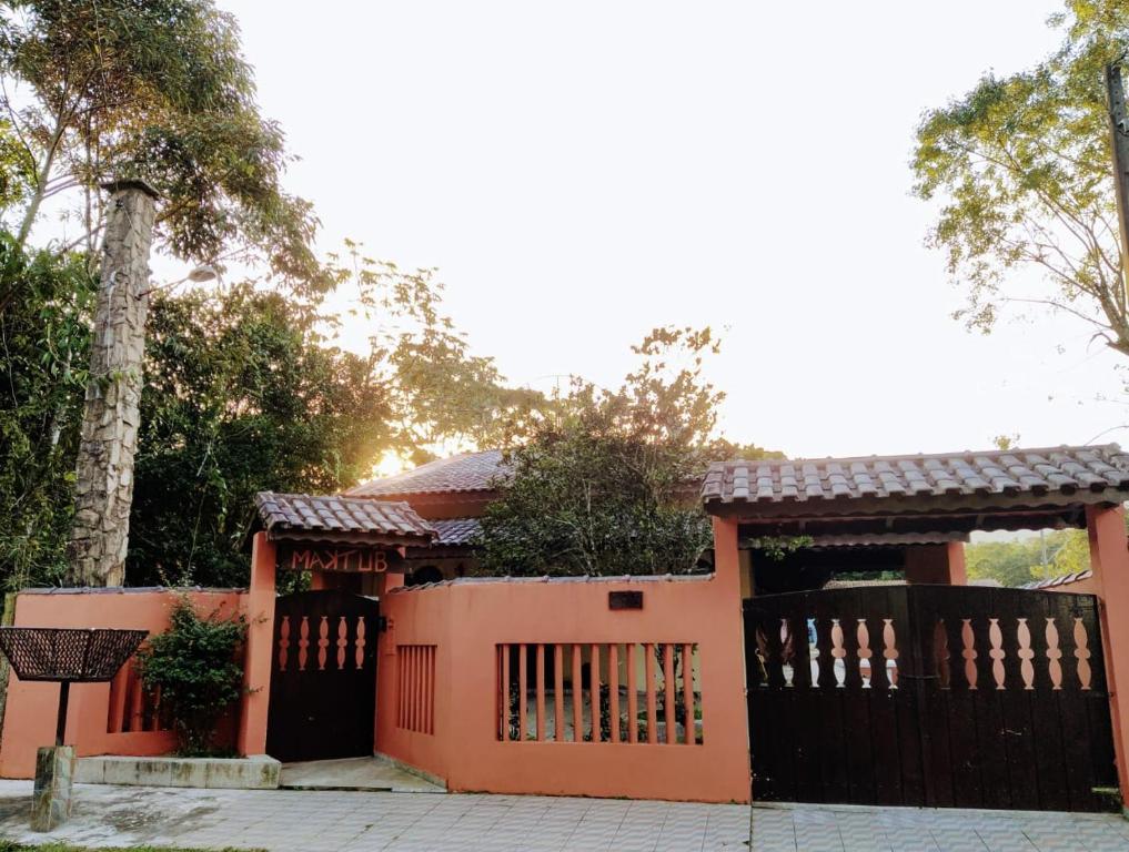 ein orangenes Haus mit einem Tor und einem Zaun in der Unterkunft Pousada Maktüb in Peruíbe