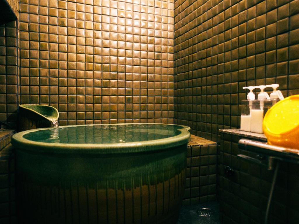 een badkamer met een groot bad en een wastafel bij Kinoya Hostel in Fuji