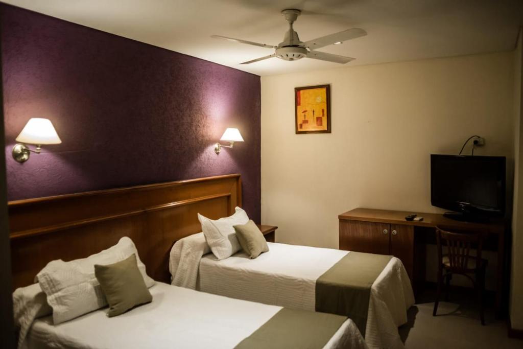 a hotel room with two beds and a flat screen tv at Hotel Ciudad in Santiago del Estero