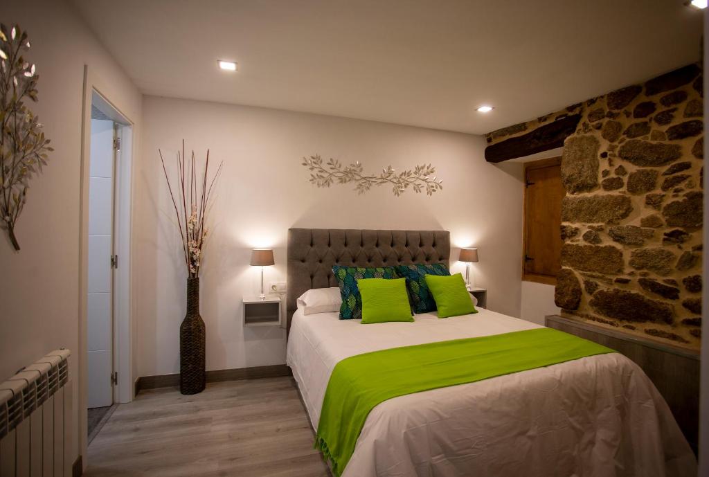 1 dormitorio con 1 cama grande con almohadas verdes en Apartamentos Casa dos Arcos, en Sober