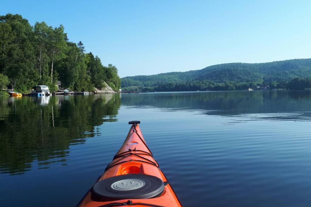 an orange kayak is on a lake with trees at Le Nid doré sur le lac (Golden Nest on the lake) in Val des Monts