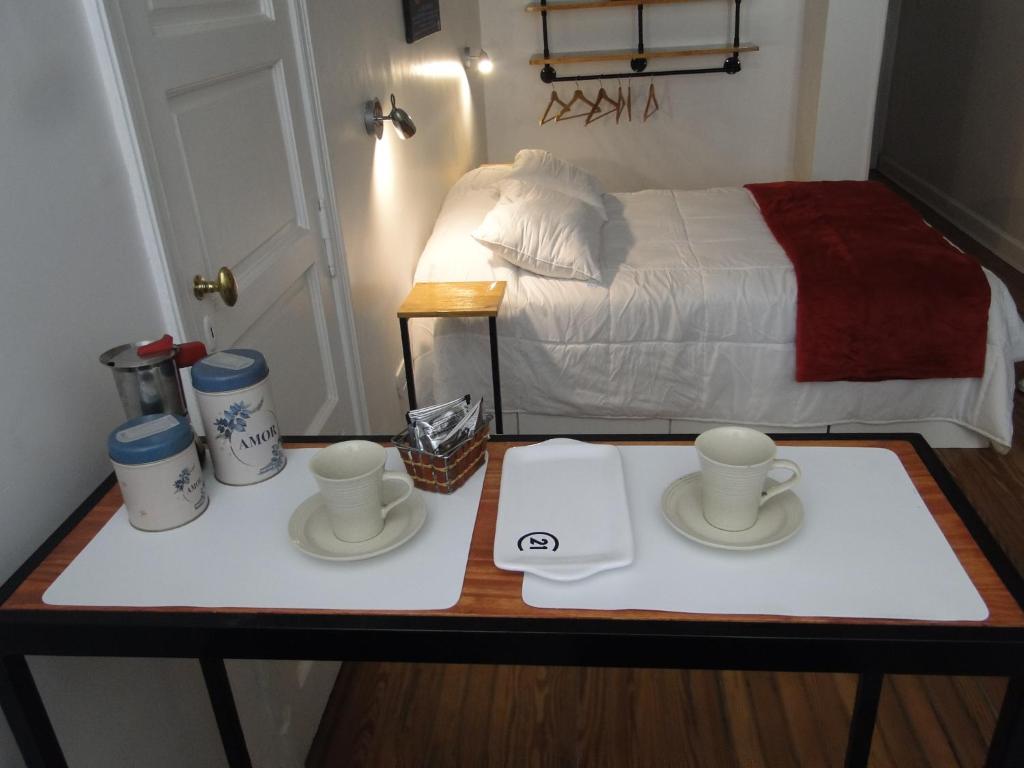 a table with two cups and plates on it with a bed at Lavalle Studio Buenos Aires in Buenos Aires