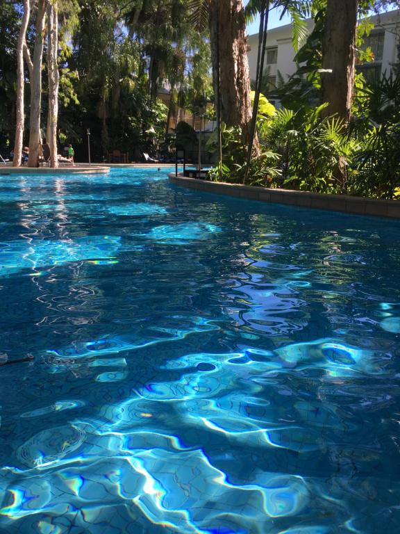 uma piscina de água azul com árvores ao fundo em PalmCove DriftAway em Palm Cove