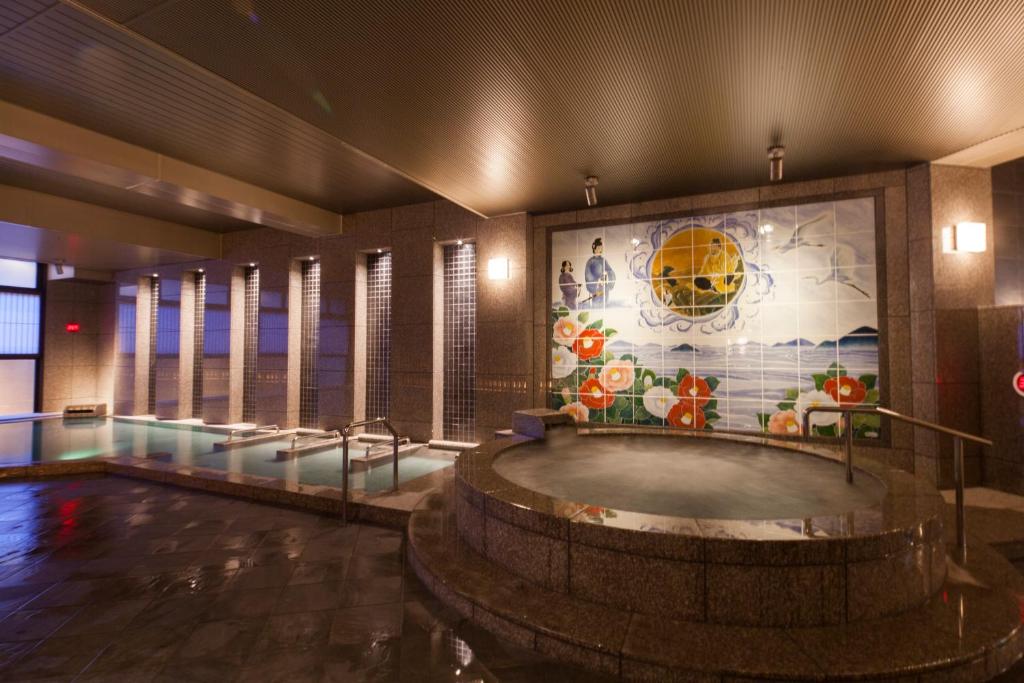 a hot tub in a room with a mosaic wall at Dogo Prince Hotel in Matsuyama