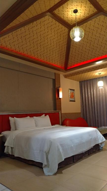 a bedroom with a large white bed with a red headboard at I Travel Motel in Kaohsiung