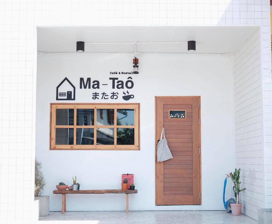 un edificio con una puerta y una señal que readsma tac en Ma-TaÔ またお Café & hostel, en Nan