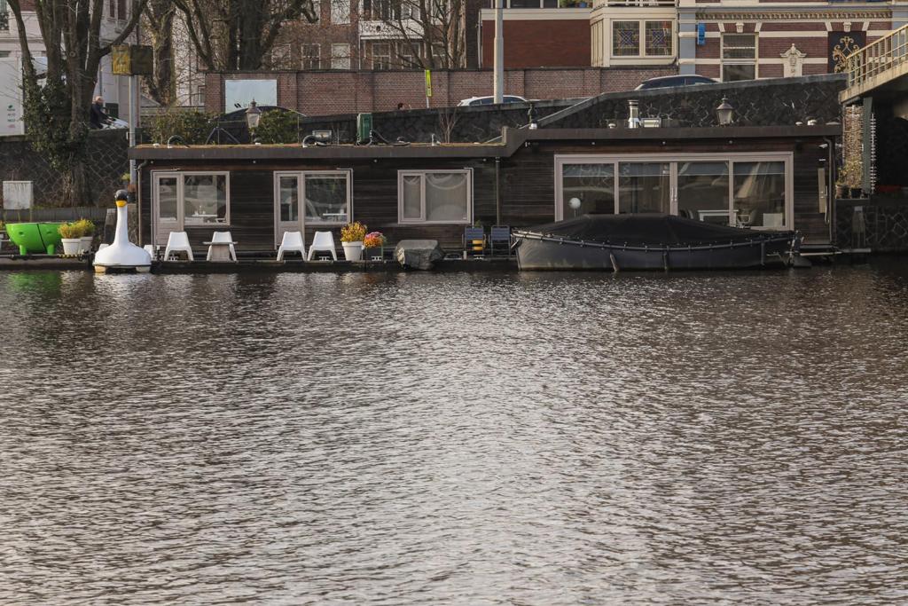 una casa con sillas y un barco en el agua en Houseboat Little Amstel, en Ámsterdam