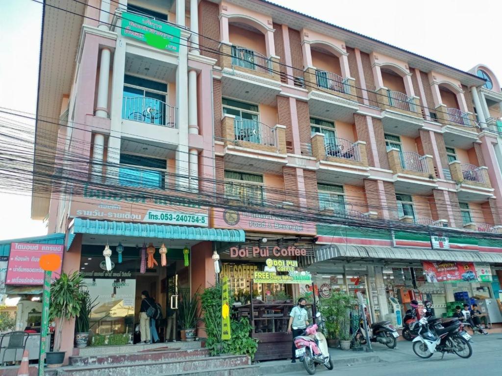 un grand bâtiment avec des motos garées devant lui dans l'établissement โรงแรมไดมอนด์แกรนด์ เฮ้าส์ แอนด์ รีสอร์ท, à Chiang Mai