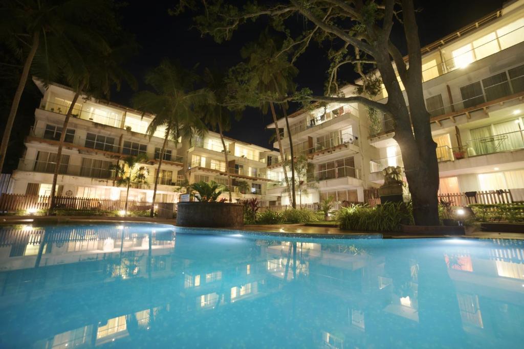 een zwembad voor een gebouw 's nachts bij Eternal Wave Apartments by Daystar Ventures in Calangute