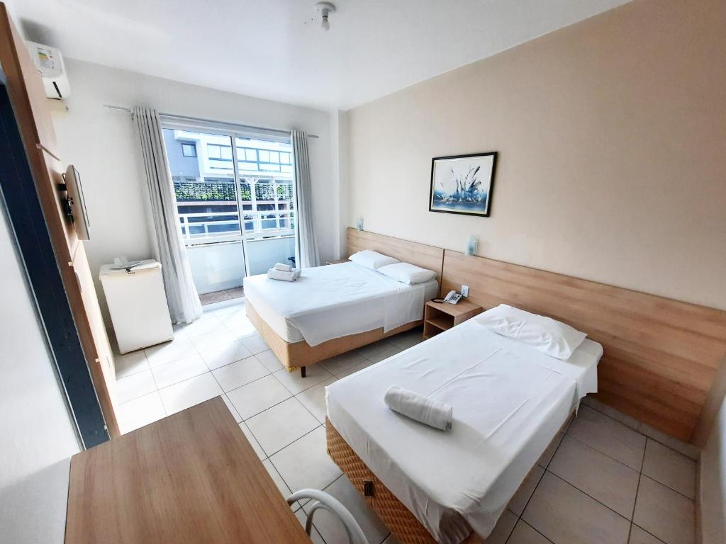 Habitación de hotel con 2 camas y ventana en Hotel Ficare Torres, en Torres