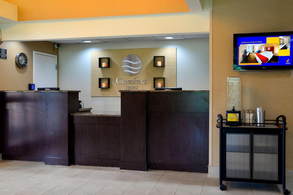 a hotel lobby with a counter and a tv on the wall at Comfort Inn University Durham - Chapel Hill in Durham