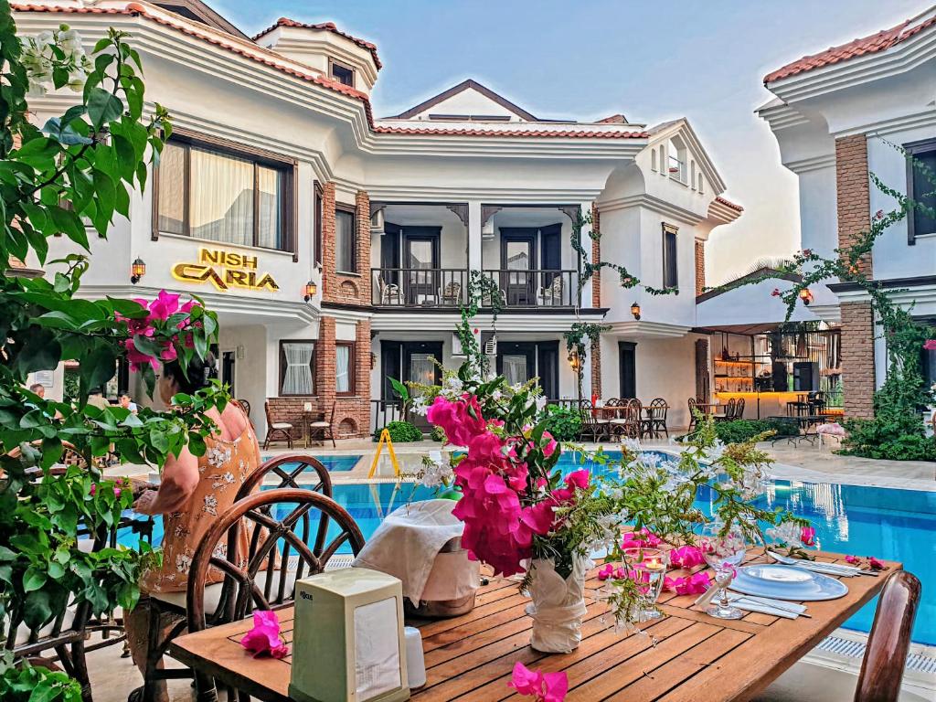 uma casa com piscina e uma mesa com flores em Dalyan Hotel Nish Caria em Dalyan