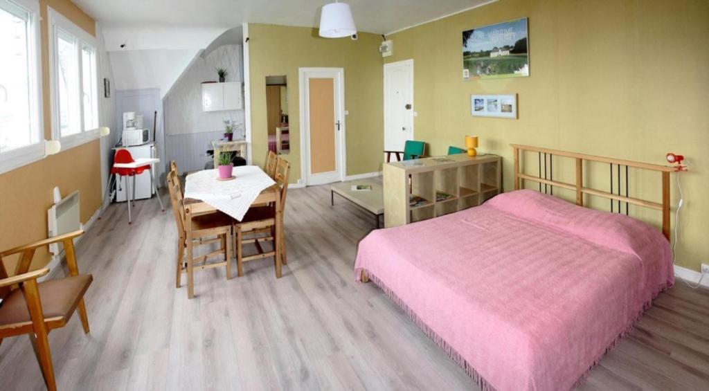 um quarto com uma cama rosa e uma mesa em Villa Normande em Le Tréport