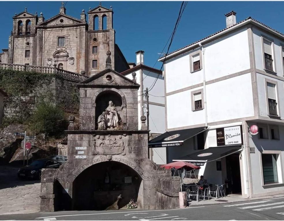 a building with a statue in front of a building with a church at Albergue con encanto d'camiño in Padrón