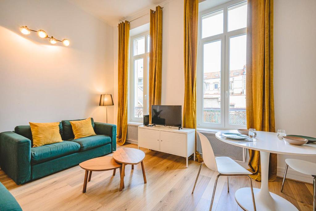 a living room with a green couch and a table at Hyper centre - Cathédrale in Reims