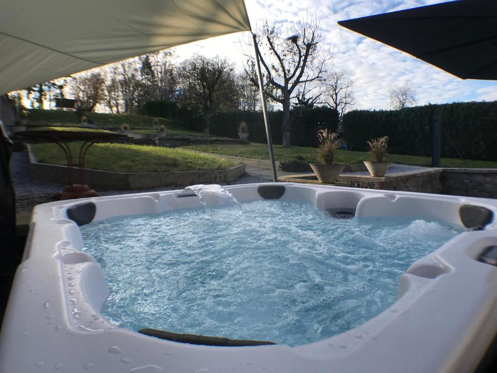 - un bain à remous dans la cour avec un parasol dans l'établissement Gite Amélie, Sauna, Spa au coeur des Vosges, à Housseras