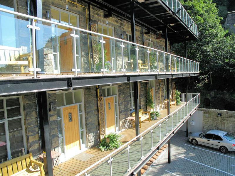 a building with yellow doors and a balcony with a car at Croft Mill in Hebden Bridge