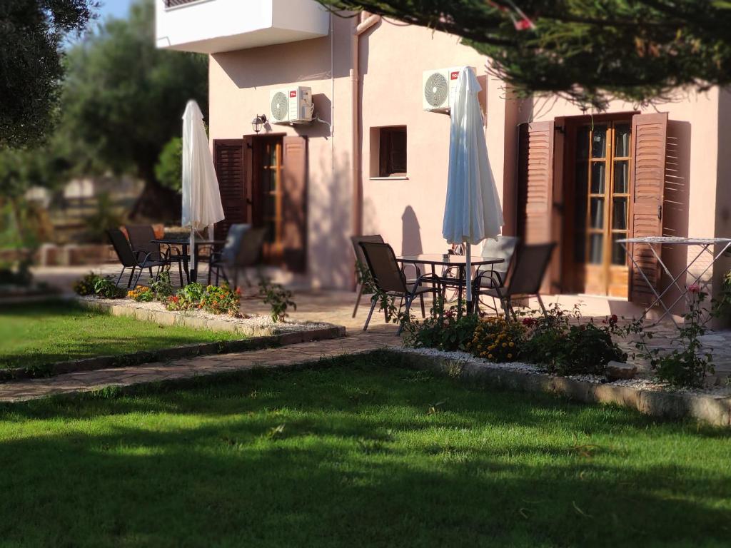 un groupe de chaises et de parasols devant une maison dans l'établissement sivotahomes-country, à Sivota