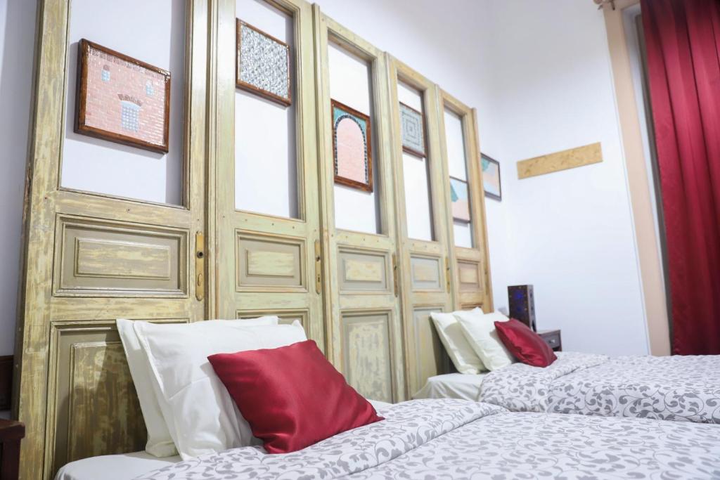 1 dormitorio con 2 camas y almohadas rojas y blancas en Cairo International Hostel Downtown, en El Cairo
